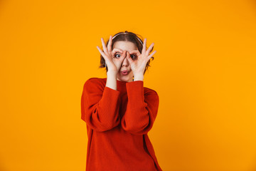 Emotional young pretty woman posing isolated over yellow wall background listening music with headphones.