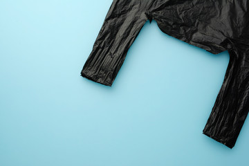 Black plastic bag on the blue background, recycle concept. Top view.