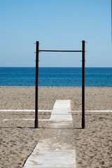 Iron frame surrounding a wooden way on the beach. It is looking like a portal leading to the sea. 
