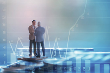 Double exposure row of coins of Two Business man and graph,saving,investment and finance concepts. Miniature people Stand behind of a red pen,soft focus and blurred style.