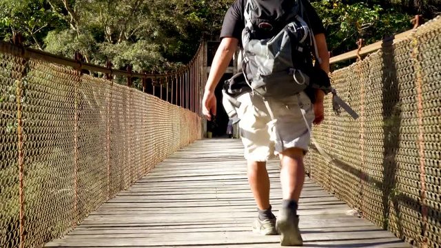 Backpacker walking across suspenion bridge .mp4