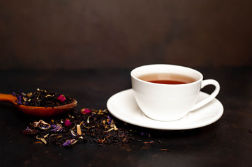 tasty tea in a white mug, scattered tea on a stone background