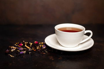 tasty tea in a white mug, scattered tea on a stone background