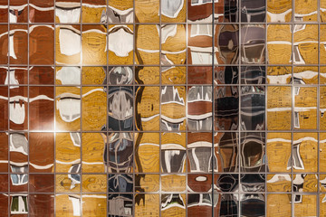 A beautiful horizontal texture of part of a colorful glass wall with reflections of a new modern building in yellow and orange and gray color