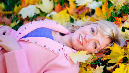 a blonde woman with blue eyes in a pink wool jumper and a blue t-shirt is lying on the ground in...