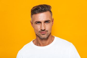 Image of sexual man 30s in white t-shirt posing at camera with confident look