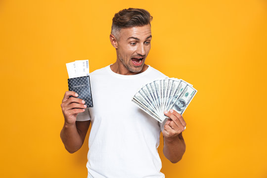 Image of rich man 30s in white t-shirt holding money fan and travel tickets