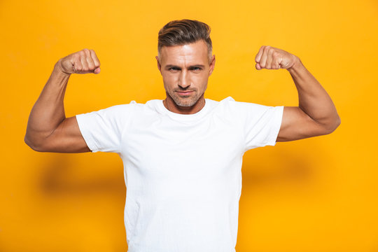 Image of european man 30s in white t-shirt raising hands and showing biceps