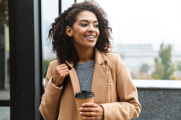 Cheerful young african woman wearing coat walking