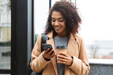 Cheerful young african woman wearing coat walking