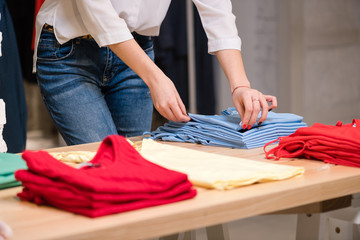 Female fold blue clothes at clothing store.