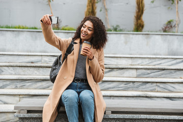 Cheerful young african woman wearing coat walking