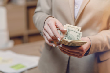 Hand giving money.  Businesswoman in eyeglasses holding dollar currency.
