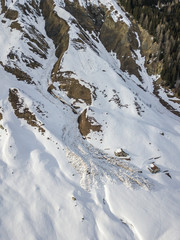 Fototapeta na wymiar Aerial view of snow avalanche on mountain slope. Wet snow in spring sliding downhill.
