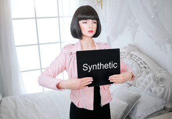 Fashion freak. Glamour girl, fake doll with empty look and short black hair is holding paper with...