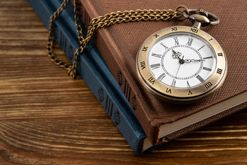 Vintage pocket watch clock with book on wooden background