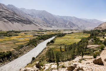 Fototapeta na wymiar Fertile Wakhan Valley with Panj river near Vrang in Tajikistan. The mountains in the background are the Hindu Kush in Afghanistan