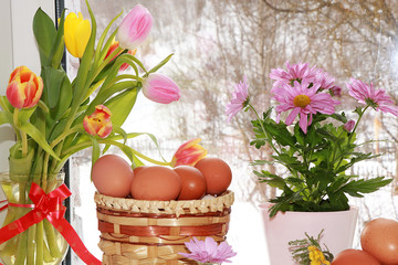 A bouquet of flowers and a basket with eggs on a rustic window, preparation for Easter, the approach of spring in the Russian village