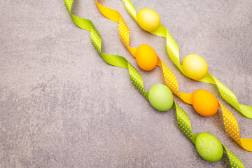 Easter eggs concept with polka dot satin ribbons. On a stone background, wallpaper, copy space, top view.