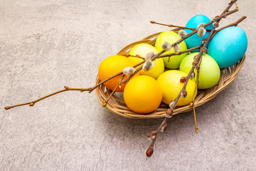 Easter eggs concept willow seals branches in a wicker basket. On a stone background, copy space, wallpaper, close up.