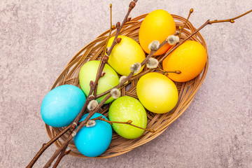 Easter eggs concept willow seals branches in a wicker basket. On a stone background, copy space, wallpaper, top view, close up.