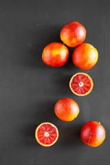 Whole and halved blood oranges on  dark surface, top view. Flat lay, overhead, from above.