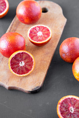 Whole and halved blood oranges on black surface, low angle view. Close-up.