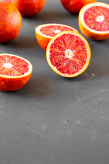 Whole and halved blood oranges on black surface, low angle view. Copy space