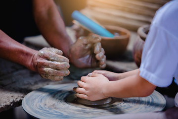 close-up to hands of potter teacher and child