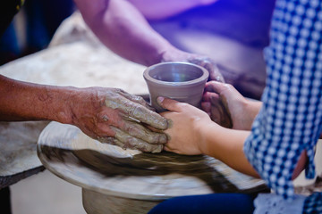 close-up to hands of potter teacher and child