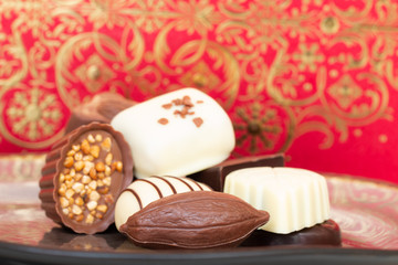 Assorted gourmet chocolate candies in different shapes and colors in the dish.