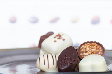 Assorted gourmet chocolate candies in different shapes and colors in the dish.