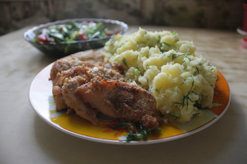 Dish consisting of fried meat and boiled potatoes and cucumber salad with green onions and tomatoes.