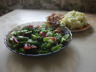 Dish consisting of fried meat and boiled potatoes and cucumber salad with green onions and tomatoes.