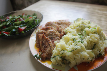 Dish consisting of fried meat and boiled potatoes and cucumber salad with green onions and tomatoes.