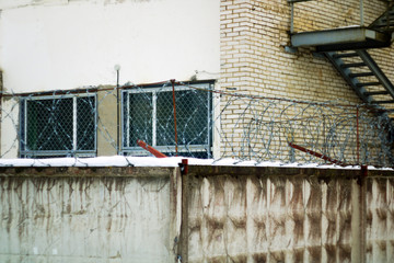 Brick building with bars on the Windows of the concrete fence with barbed wire