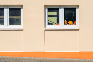 Pile of Orange Construction Helmets On the Windowsill Inside the Building. . Exterior of a Plastered Building on a Sunny Day. Copy Space