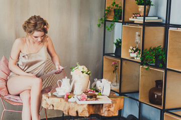young woman sitting at home in a chair at Breakfast and reading. 