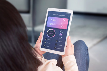 Smart home control automation app concept. Woman use tablet with modern flat desing app to control living room temperature, ventilation, lighting.