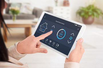 Modern software to home control on tablet display. Woman control temperature in living room....