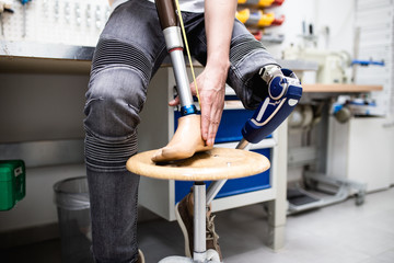 Disabled man working in amputee shop for production prosthetic extremity parts. - obrazy, fototapety, plakaty
