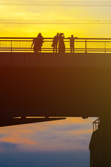 Silhouettes a Group of People on the High Bridge on a Background of Yellow Sunset