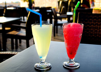 two glasses with red and yellow coctails on the tadle