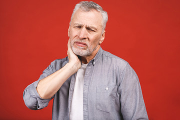 Obraz premium Senior aged man suffering from toothache on red background.