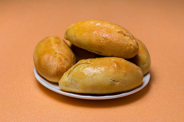 Pies with meat, cabbage or any filling. Baked pies in the oven. On a white plate.