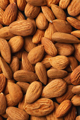 yellow almond nuts scattered on black paper background