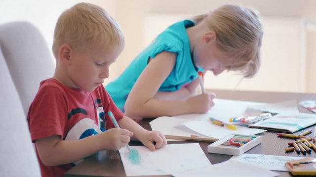 Boy and Girl are Drawing on Paper by Color Pencils Together at the Desk. Brother and Sister Leisure Activity at Home