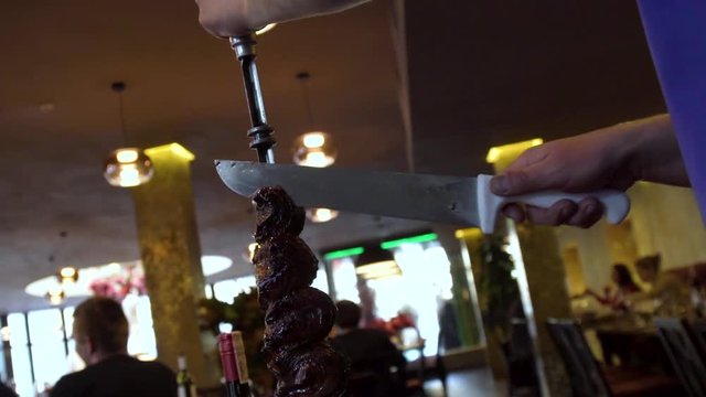 Close up male hand chopping meat with big knife