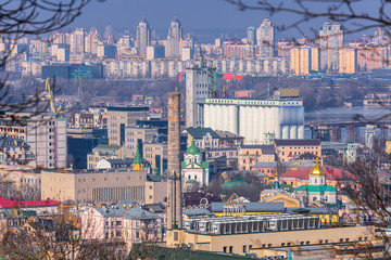Obraz premium Early spring at sunny evening in warm weather. Industrial zone and residential areas Podin and northern suburbs Obolon in Kyiv on the right bank of the Dnipro River. Ukraine Mar. 6, 2019