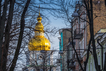 Fototapeta na wymiar Early spring at sunny evening in warm weather. Gilded dome of the bell tower of St. Michael's Monastery, Kyiv, Ukraine Mar. 6, 2019